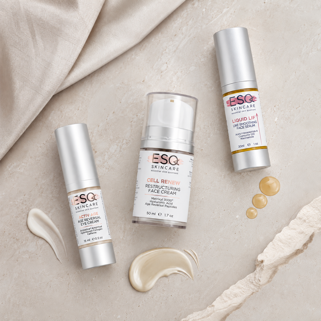 Three ESQ Skincare cosmetic tubes arranged on a light beige textured surface with draped fabric and cream product swatches. The products include a Hyalu-Cel Peptide Cream tube, a Cell Renew Restructuring Face Cream pump bottle, and a Liquid Lift Wrapping Face Cream tube.