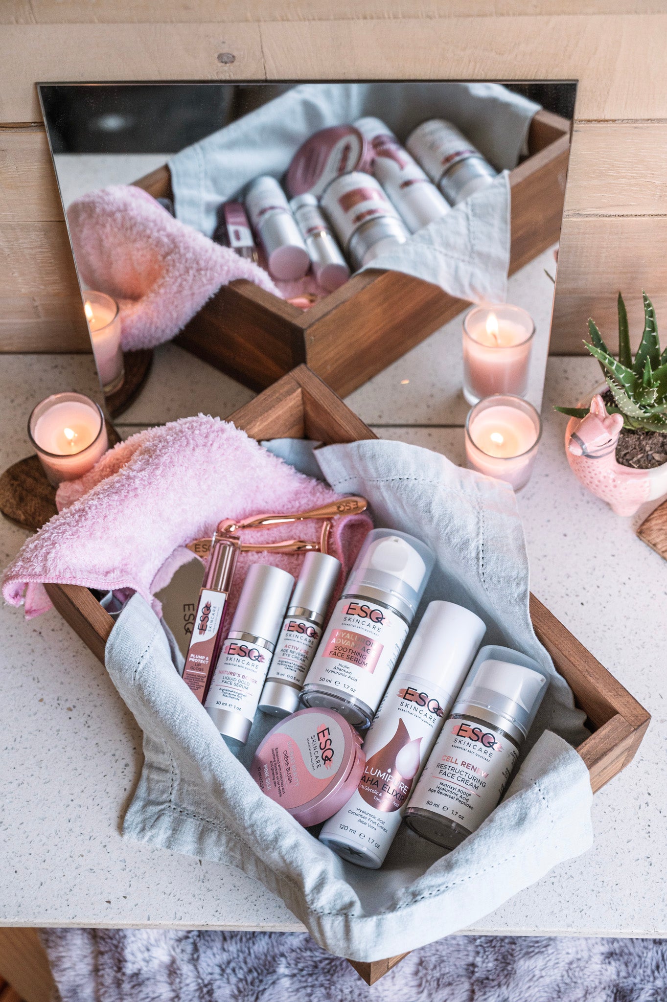 ESG skincare products displayed on a wooden tray with candles and a plant in the background.