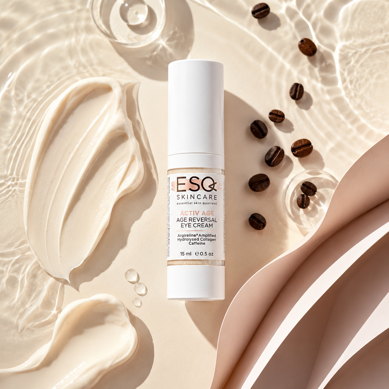 A white cosmetic eye cream tube labeled ESG Skincare Age Reversal Eye Cream, styled on a warm beige surface with cream swatches, coffee beans, and clear droplets.
