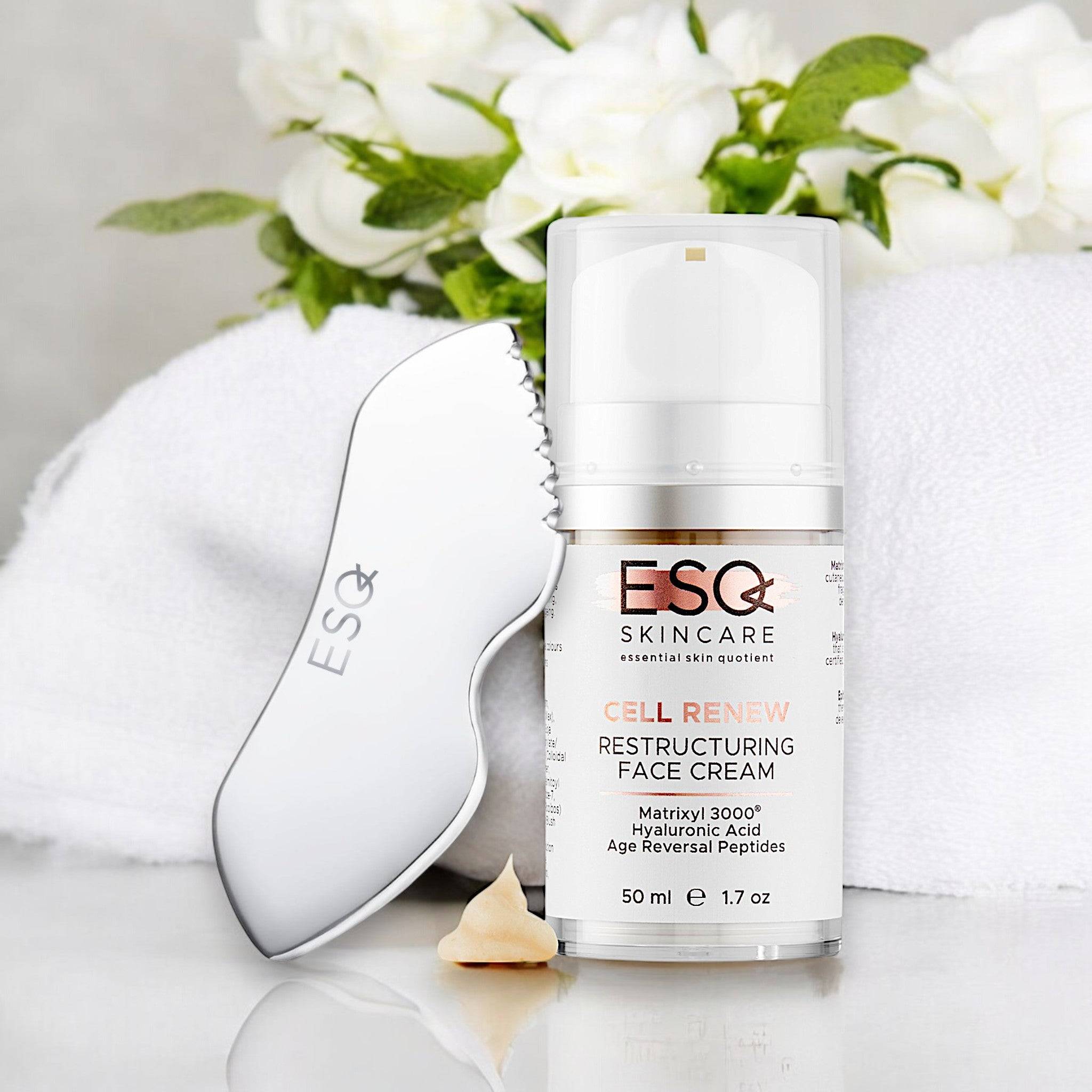 Firm & Glow Power Pair gift set featuring a restructuring face cream with Matrixyl 3000 and a sleek face massage tool, surrounded by white flowers and a towel.