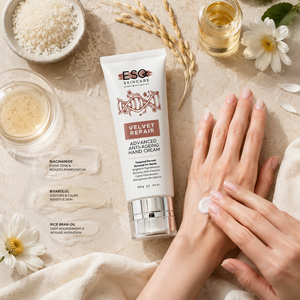 A tube of ESO Skincare Velvet Repair Advanced Anti-Aging Hand Cream is shown on a beige fabric surface next to a person's hands applying cream. The scene is styled with skincare ingredients and props including rice, oats, and small jars.
