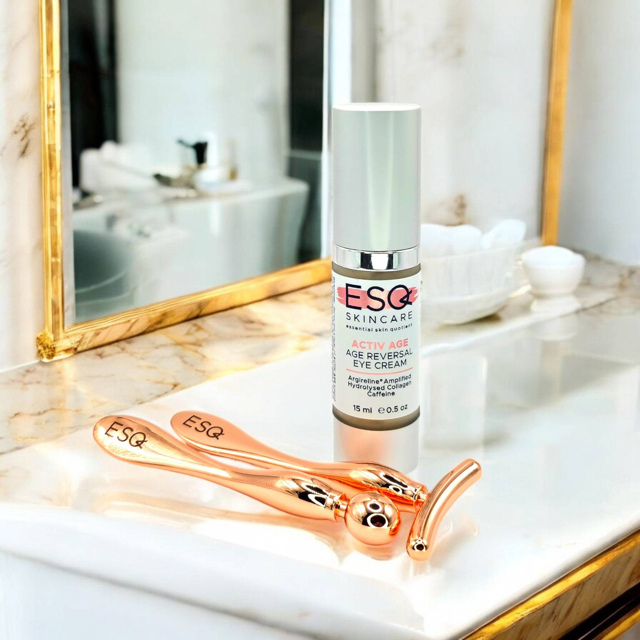 Eye Revive Luxury Gift Set featuring Argireline Amplified & Caffeine eye cream with a rose gold face roller and massage tool on a marble vanity.