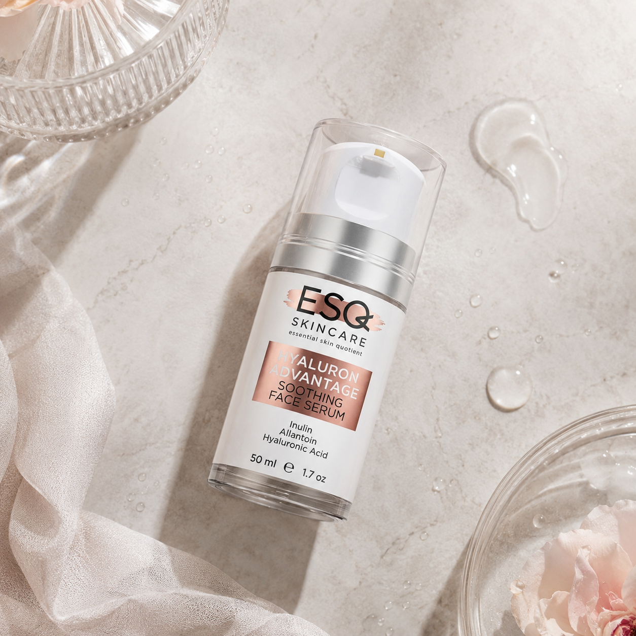 ESQ Skincare Hyaluron Vantage Soothing Face Serum in a clear pump bottle with a white cap, styled on a textured light marble surface with water droplets, sheer white fabric, and glass bowls.