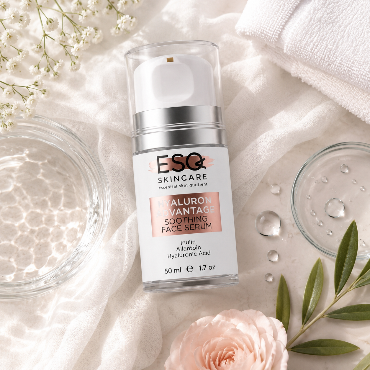 A bottle of ESC Skincare Hyaluron Advantage Soothing Face Serum is styled in a flat lay on white fabric with a pink rose, baby's breath, green leaves, and glass jars.