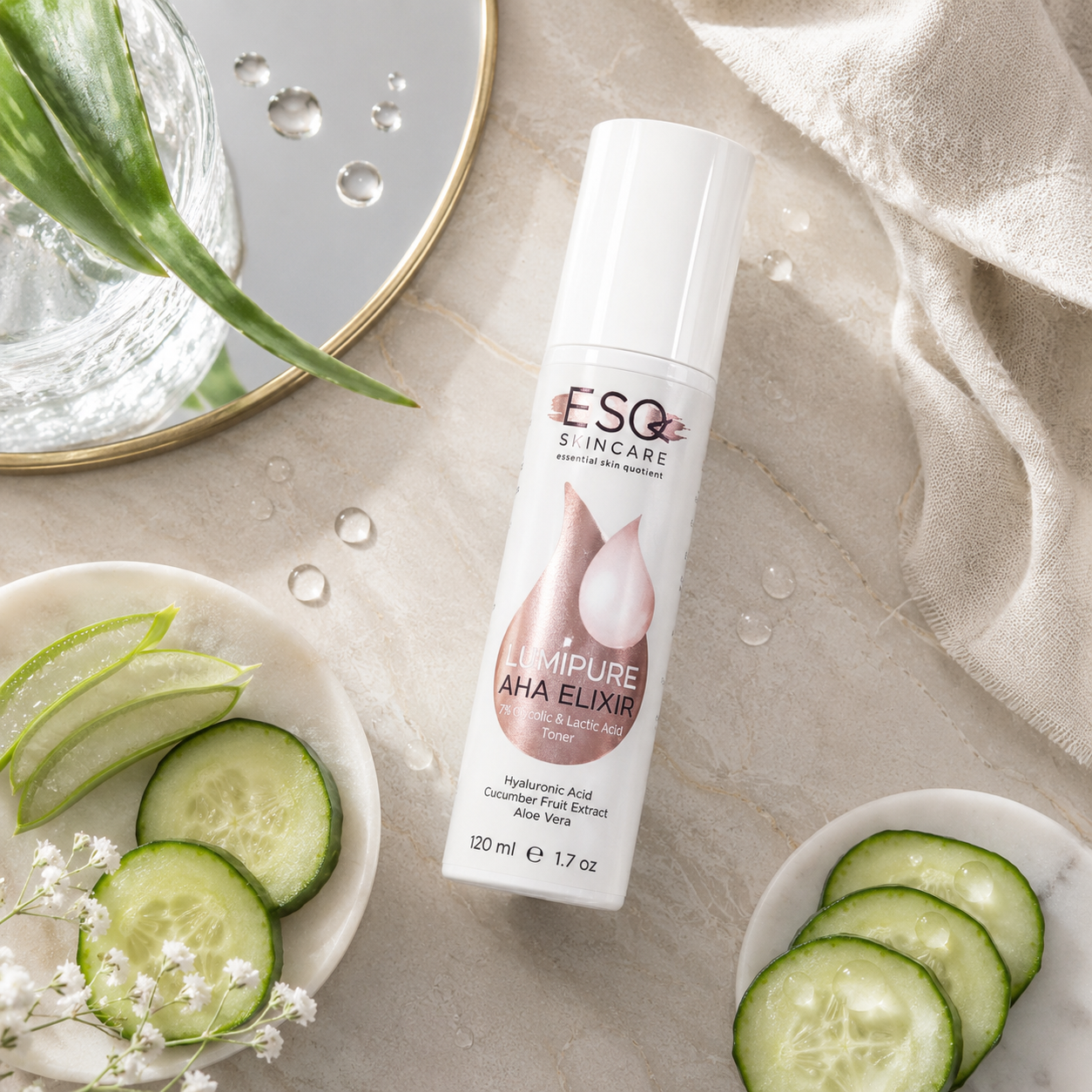 A bottle of ESQ Skin Care Lumipure AHA Elixir skincare serum, styled in a flat-lay arrangement with cucumber slices, a glass, and a textured beige fabric background.
