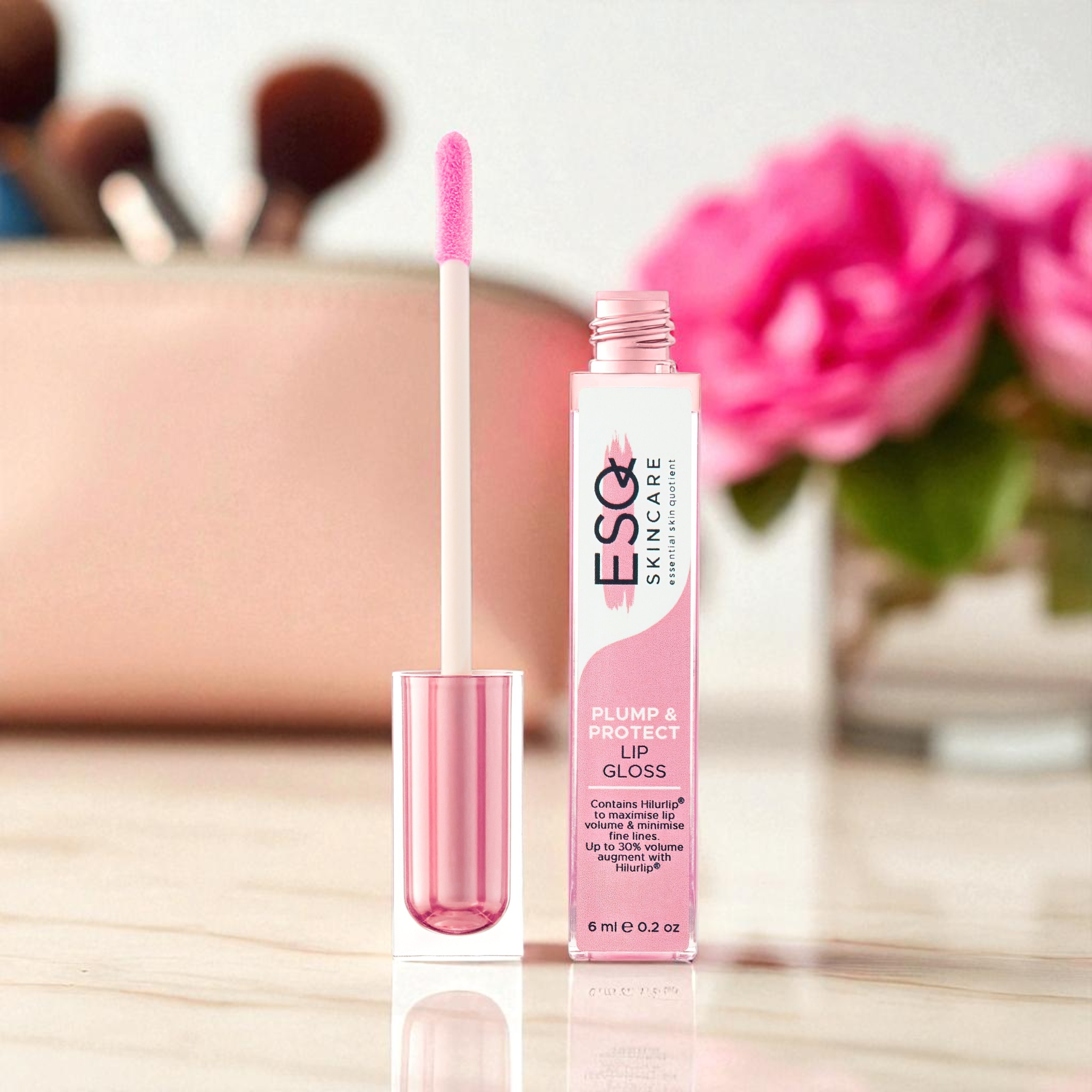 ESQ Skincare lip gloss with applicator on a blurred makeup background