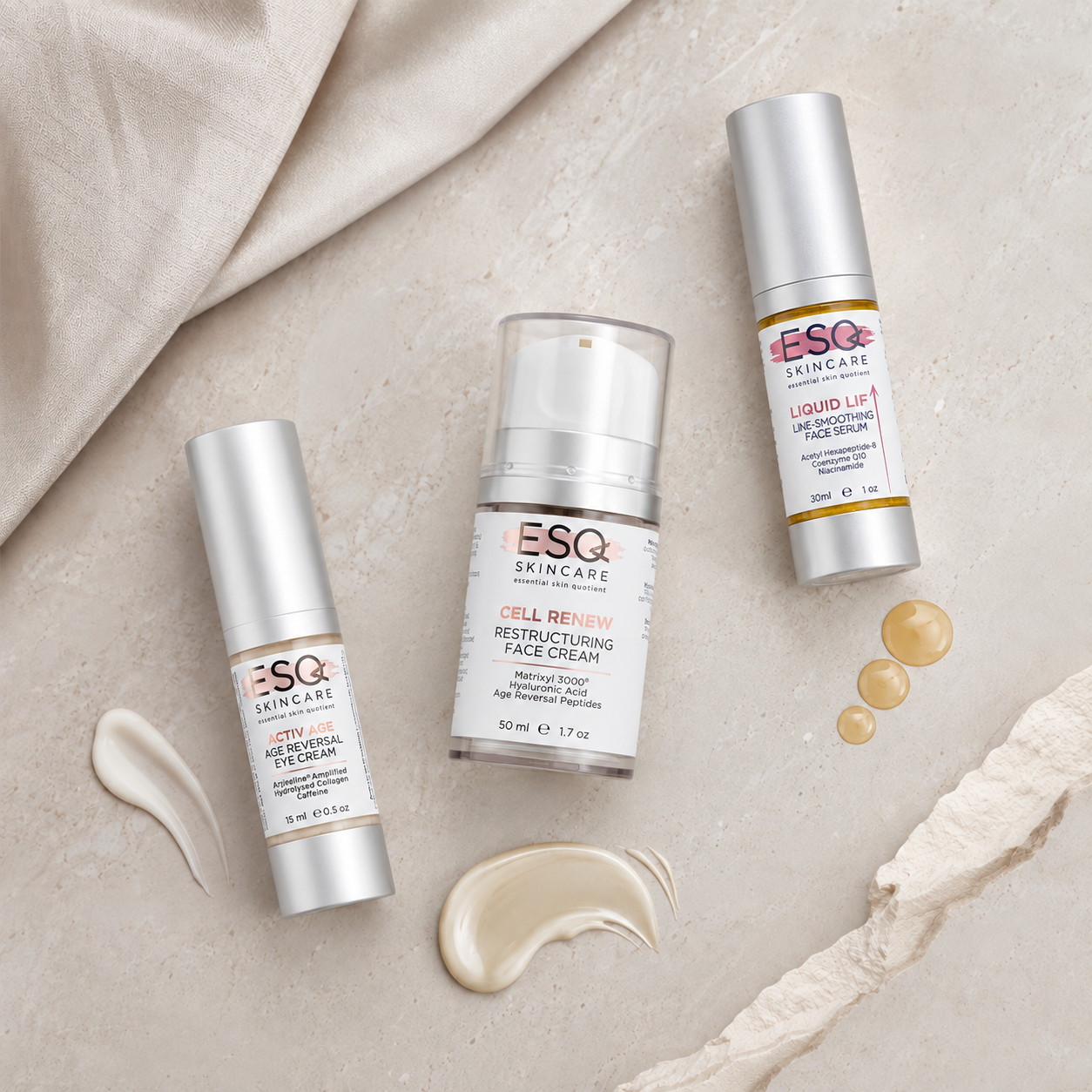 Three ESQ Skincare cosmetic tubes arranged on a light beige textured surface with draped fabric and cream product swatches. The products include a Hyalu-Cel Peptide Cream tube, a Cell Renew Restructuring Face Cream pump bottle, and a Liquid Lift Wrapping Face Cream tube.