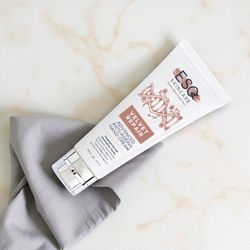 Tube of E&Q skincare cream on a marble surface with a gray cloth