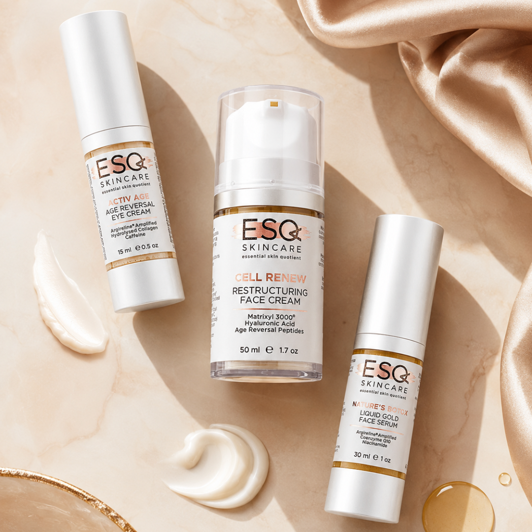 Three ESQ Skincare cosmetic bottles arranged on a beige marble surface with cream swirls and draped satin fabric. The products include an eye cream, a restructuring face cream in a clear pump bottle, and a liquid face serum.