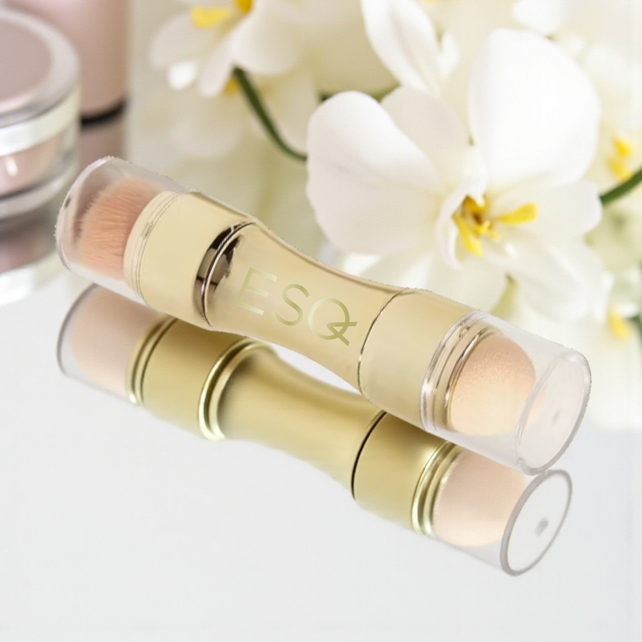 Two cosmetic sticks with a brand logo on a light background with flowers